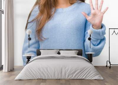 Young beautiful brunette woman wearing blue winter sweater over isolated background showing and pointing up with fingers number five while smiling confident and happy. Wall mural