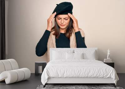 Young beautiful brunette woman wearing casual french beret over white background with hand on head for pain in head because stress. Suffering migraine. Wall mural