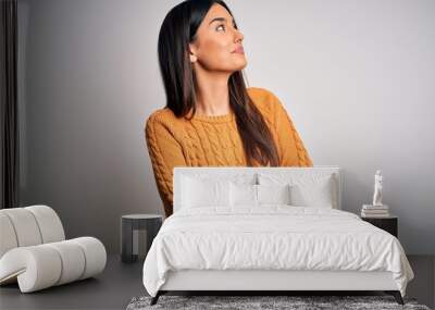 Young beautiful brunette woman wearing casual sweater over isolated white background looking to the side with arms crossed convinced and confident Wall mural