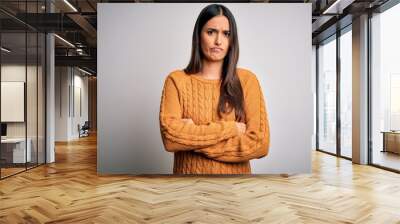 Young beautiful brunette woman wearing casual sweater over isolated white background skeptic and nervous, disapproving expression on face with crossed arms. Negative person. Wall mural