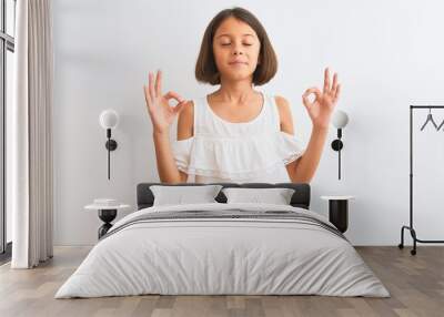 Young beautiful child girl wearing casual dress standing over isolated white background relax and smiling with eyes closed doing meditation gesture with fingers. Yoga concept. Wall mural