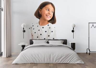 Young beautiful child girl wearing casual t-shirt standing over isolated white background looking away to side with smile on face, natural expression. Laughing confident. Wall mural