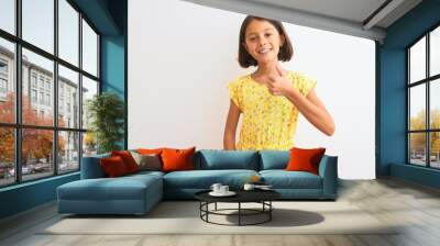 Young beautiful child girl wearing yellow floral dress standing over isolated white background doing happy thumbs up gesture with hand. Approving expression looking at the camera showing success. Wall mural