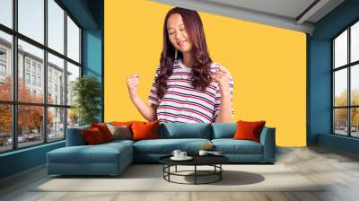 Young beautiful chinese girl wearing casual clothes very happy and excited doing winner gesture with arms raised, smiling and screaming for success. celebration concept. Wall mural