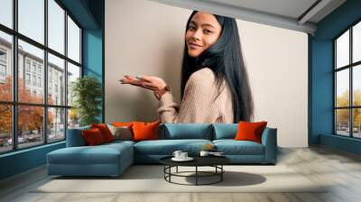 Young beautiful chinese woman wearing casual sweater over isolated white background pointing aside with hands open palms showing copy space, presenting advertisement smiling excited happy Wall mural