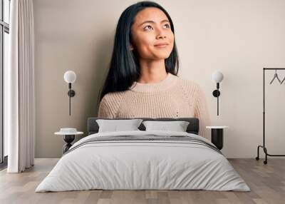 Young beautiful chinese woman wearing casual sweater over isolated white background smiling looking to the side and staring away thinking. Wall mural