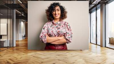 Young beautiful curly arab woman wearing floral t-shirt standing over isolated white background happy face smiling with crossed arms looking at the camera. Positive person. Wall mural