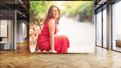 Young beautiful girl smiling happy and confident sitting on bench at the town park with a smile on face Wall mural