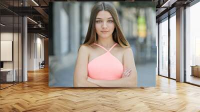 Young beautiful girl standing with serious expression and arms crossed gesture at street Wall mural