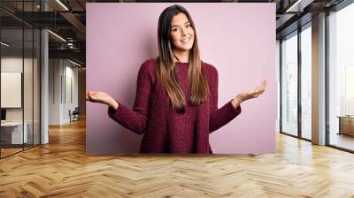 Young beautiful girl wearing casual sweater over isolated pink background smiling showing both hands open palms, presenting and advertising comparison and balance Wall mural