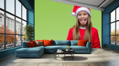 Young beautiful girl wearing christmas hat over isolated background sticking tongue out happy with funny expression. Emotion concept. Wall mural