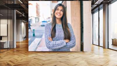 Young beautiful hispanic girl smiling happy and with crossed arms standing at the city. Wall mural