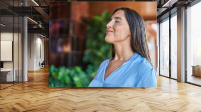 Young beautiful hispanic woman breathing with closed eyes at street Wall mural