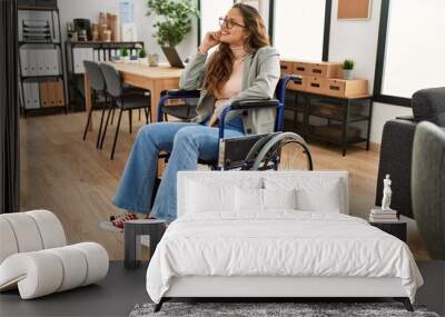 Young beautiful hispanic woman business worker smiling confident sitting on wheelchair at office Wall mural