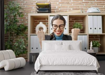 Young beautiful hispanic woman business worker using laptop celebrating at office Wall mural