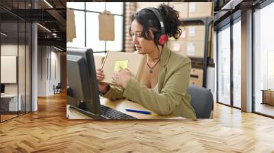 Young beautiful hispanic woman ecommerce business worker having video call showing package at office Wall mural