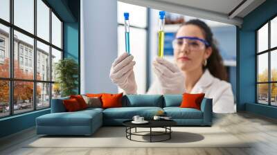 Young beautiful hispanic woman scientist holding test tubes at laboratory Wall mural