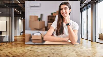 Young beautiful hispanic woman smiling confident leaning on package at new home Wall mural