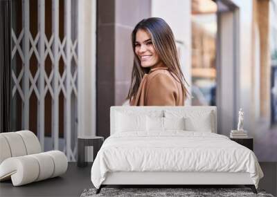 Young beautiful hispanic woman smiling confident looking to the side at street Wall mural