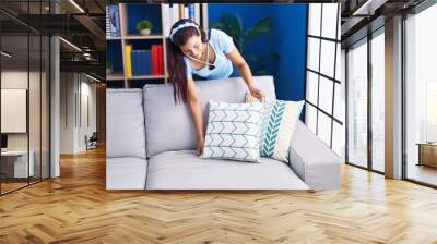 Young beautiful hispanic woman smiling confident organizing sofa at home Wall mural