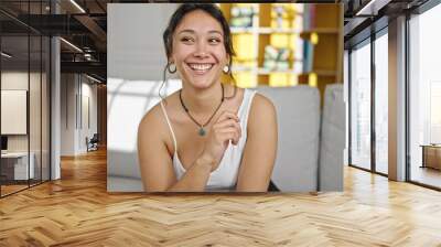 Young beautiful hispanic woman smiling confident sitting on sofa looking to the side at home Wall mural