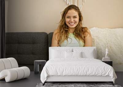 Young beautiful hispanic woman smiling confident sitting on sofa with arms crossed gesture at home Wall mural