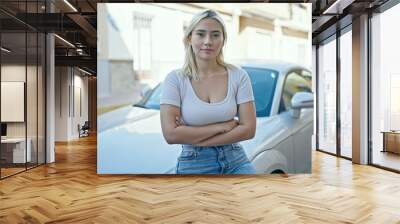 Young beautiful hispanic woman standing by car with serious expression and arms crossed gesture at street Wall mural