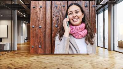 Young beautiful hispanic woman talking on smartphone wearing scarf at street Wall mural