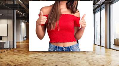 Young beautiful hispanic woman wearing casual clothes success sign doing positive gesture with hand, thumbs up smiling and happy. cheerful expression and winner gesture. Wall mural