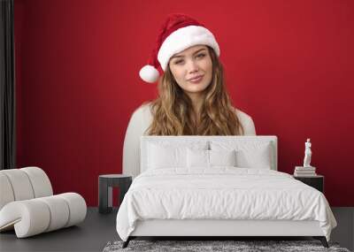 Young beautiful hispanic woman wearing christmas hat standing with relaxed expression over isolated red background Wall mural