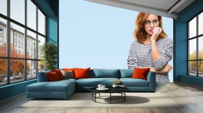 Young beautiful woman over isolated background wearing glasses looking stressed and nervous with hands on mouth biting nails. Anxiety problem. Wall mural