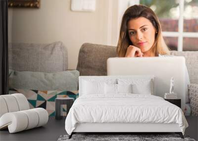 Young beautiful woman smiling using laptop on the sofa looking confident to the camera. Wall mural