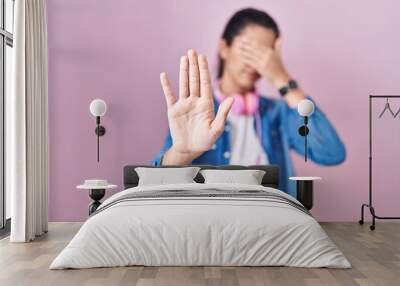 Young beautiful woman standing over pink background covering eyes with hands and doing stop gesture with sad and fear expression. embarrassed and negative concept. Wall mural