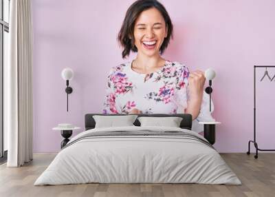 Young beautiful woman wearing casual clothes celebrating surprised and amazed for success with arms raised and eyes closed Wall mural