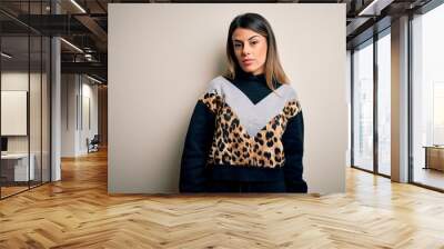 Young beautiful woman wearing casual sweatshirt standing over isolated white background Relaxed with serious expression on face. Simple and natural looking at the camera. Wall mural