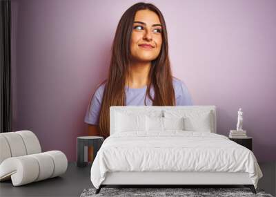 Young beautiful woman wearing casual t-shirt standing over isolated pink background smiling looking to the side and staring away thinking. Wall mural