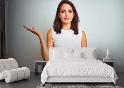 Young beautiful woman wearing dress standing over white isolated background smiling cheerful presenting and pointing with palm of hand looking at the camera. Wall mural