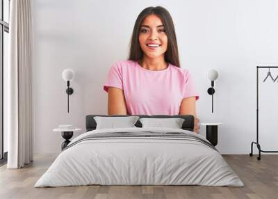 Young beautiful woman wearing pink casual t-shirt standing over isolated white background happy face smiling with crossed arms looking at the camera. Positive person. Wall mural