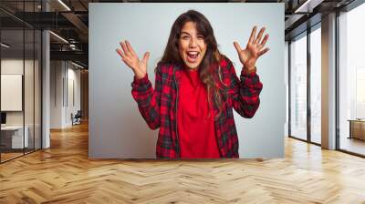 Young beautiful woman wearing red t-shirt and jacket standing over white isolated background celebrating crazy and amazed for success with arms raised and open eyes screaming excited. Winner concept Wall mural