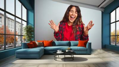 Young beautiful woman wearing red t-shirt and jacket standing over white isolated background celebrating mad and crazy for success with arms raised and closed eyes screaming excited. Winner concept Wall mural