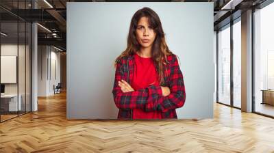 Young beautiful woman wearing red t-shirt and jacket standing over white isolated background skeptic and nervous, disapproving expression on face with crossed arms. Negative person. Wall mural