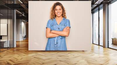 Young beautiful woman with blue eyes wearing casual denim dress over white background happy face smiling with crossed arms looking at the camera. Positive person. Wall mural