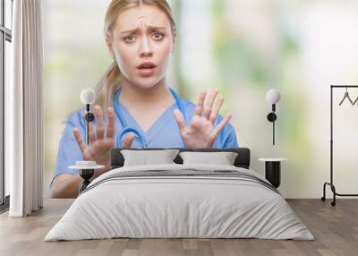 young blonde surgeon doctor woman over isolated background afraid and terrified with fear expression Wall mural