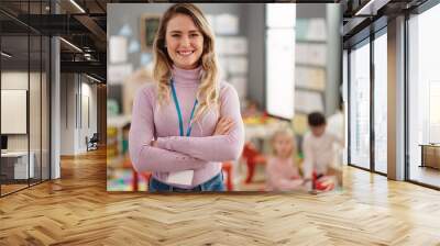 Young blonde woman teacher smiling confident standing with arms crossed gesture at kindergarten Wall mural