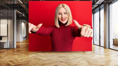 Young blonde woman wearing casual clothes approving doing positive gesture with hand, thumbs up smiling and happy for success. winner gesture. Wall mural