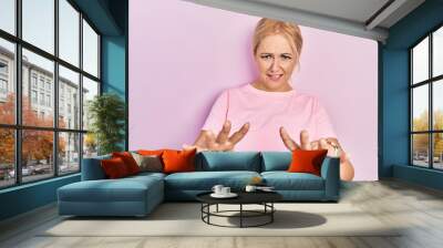 Young blonde woman wearing casual pink t shirt afraid and terrified with fear expression stop gesture with hands, shouting in shock. panic concept. Wall mural