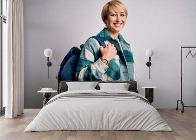 Young blonde woman with short hair wearing travel backpack over isolated background with a happy face standing and smiling with a confident smile showing teeth Wall mural