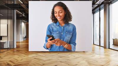 Young brazilian woman using smartphone standing over isolated white background with a happy face standing and smiling with a confident smile showing teeth Wall mural