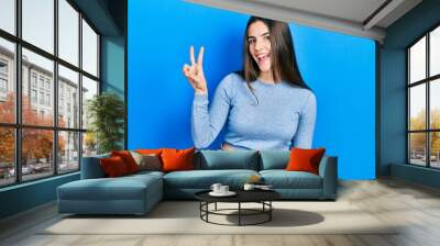 Young brunette teenager wearing casual sweater showing and pointing up with fingers number two while smiling confident and happy. Wall mural