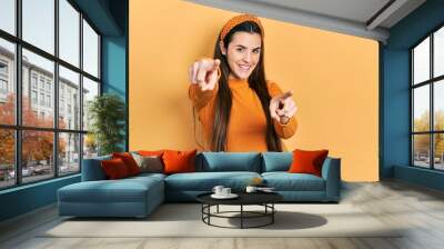 Young brunette teenager wearing casual yellow sweater pointing to you and the camera with fingers, smiling positive and cheerful Wall mural